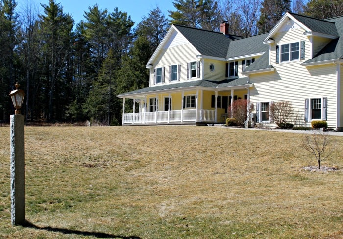 brown dormant grass in front lawn of large yellow house