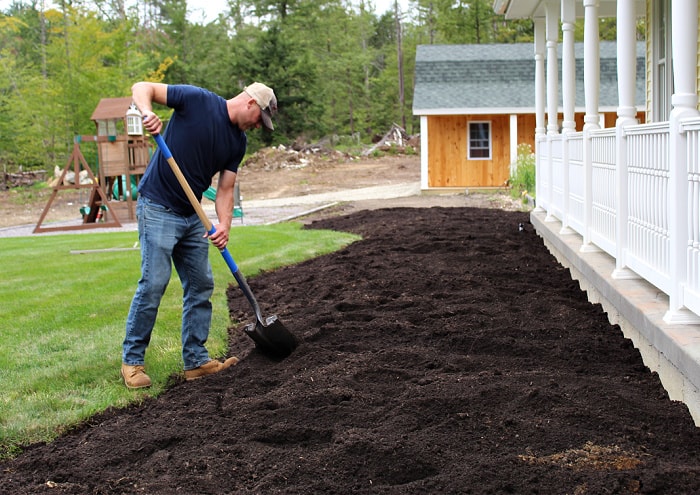 man adding compost to landscape bed